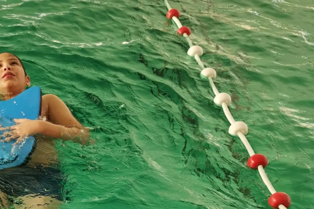 A child practising floating on their back with a kickboard.